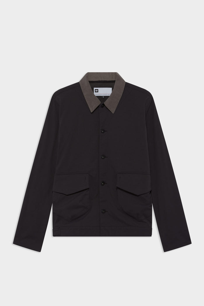 The 686 Men's Unwork® Everywhere Jacket by 686 features a black design with a brown collar, front flap pockets, and long sleeves, shown on a plain white background.