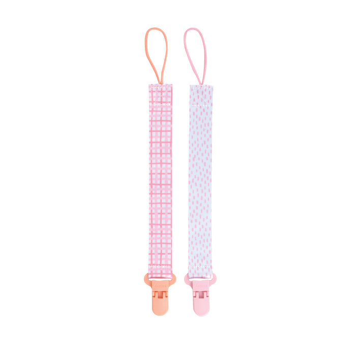 The Cloth Pacifier Clip (2 Pack) includes one pink checkered clip and one white clip with pink dots. Each baby pacifier holder features a top loop and a plastic bottom clip for easy, secure use.