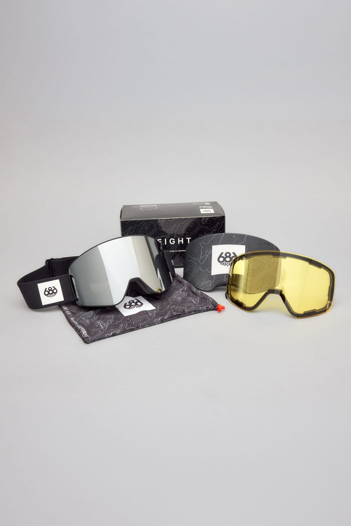 Sure! Here is your rewritten sentence: The 686 SMARTY® Magnetic Goggle by 686 is displayed on a gray background, featuring a black strap, a silver lens with an included yellow replacement lens, a patterned pouch, and a black retail box.