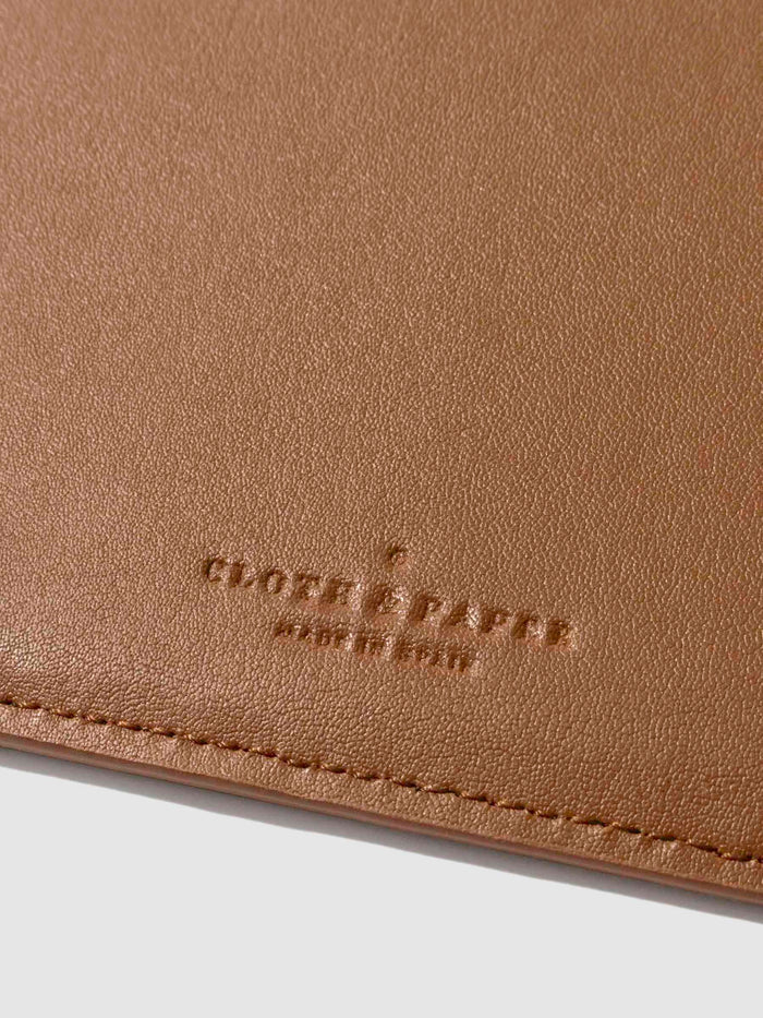 Closeup of clay brown folio's textured vegan leather and stamped Cloth and Paper logo.