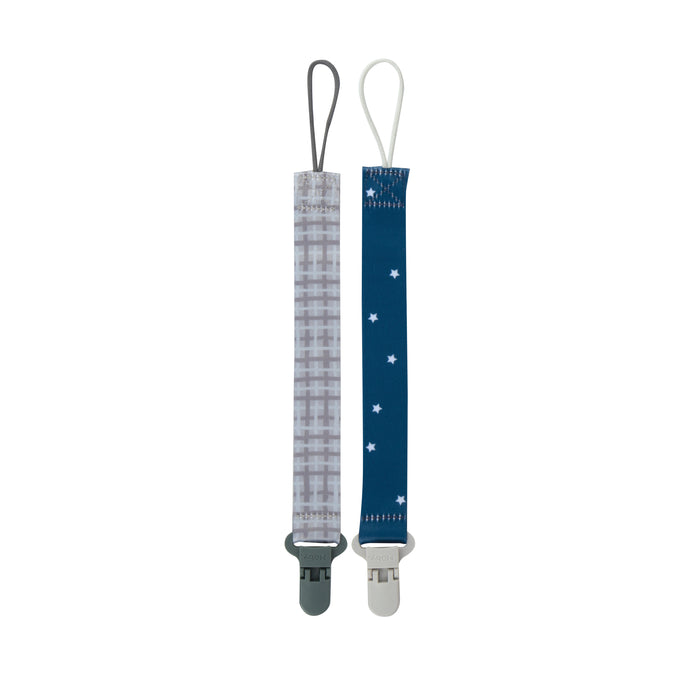 The Cloth Pacifier Clip (2 Pack) includes one with a gray plaid pattern and clip, and another with a blue background, white stars, and white clip. Both feature top loops for attaching pacifiers.