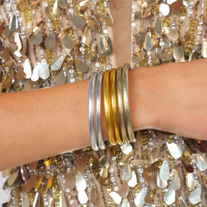 Essentials Core Mixed Stack featuring silver and gold bangles against a shimmering backdrop.