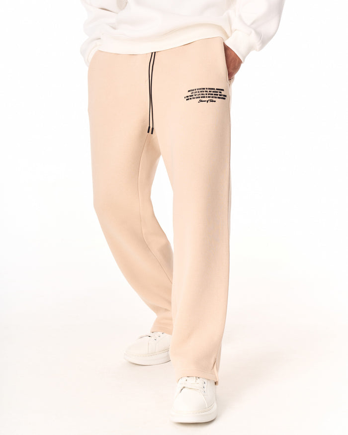 Martin Valen MV beige baggy sweatpants, back view showing ankle, split hem and partially visible white sneakers