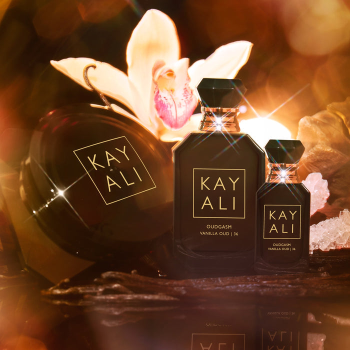 Three 'KAYALI' perfume bottles with a decorative background featuring flowers and lights.