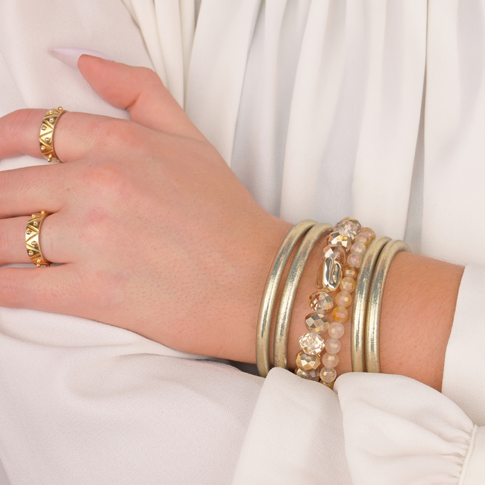 a hand with many gold bracelets
