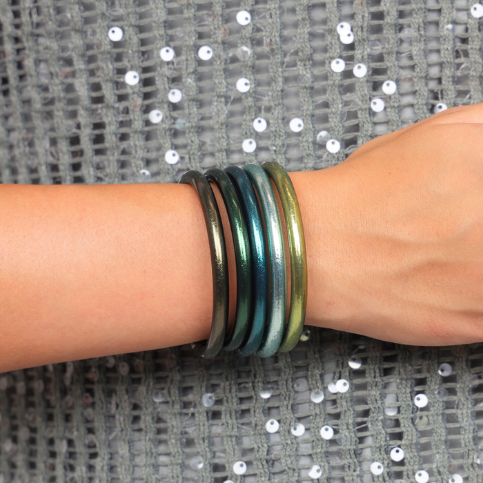 A close-up of The Twilight Tide Stack Bangle Bracelets layered on a wrist, showcasing coastal tones and sleek design.